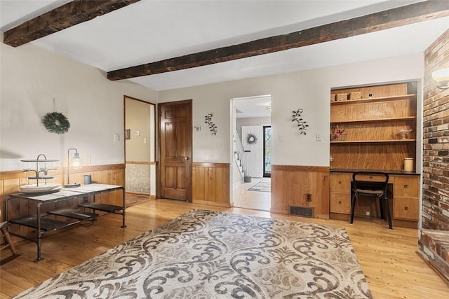 office area with beam ceiling, visible vents, wainscoting, and wood finished floors