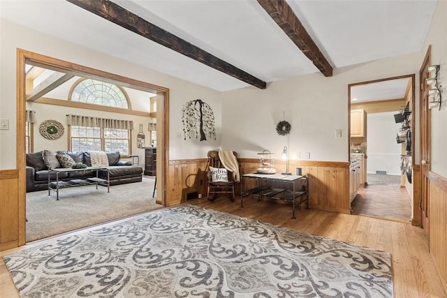living room featuring light wood-style flooring, wainscoting, and beamed ceiling
