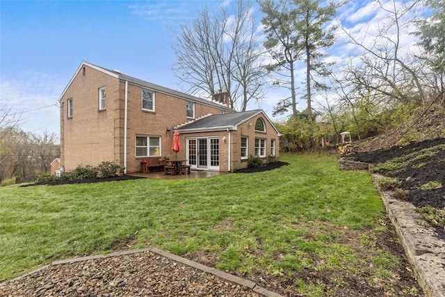 rear view of house featuring a lawn, brick siding, and a patio