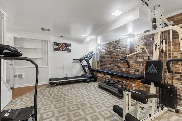 workout room featuring crown molding, brick wall, and visible vents