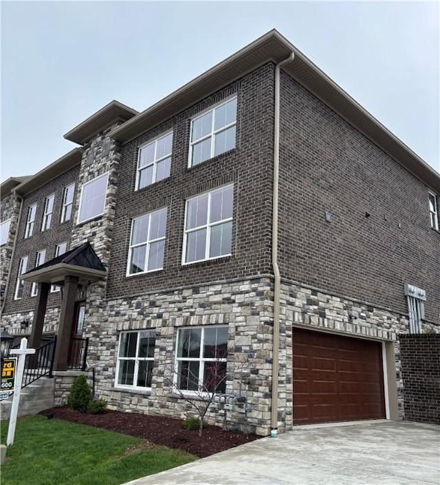 view of property featuring a garage, stone siding, and concrete driveway