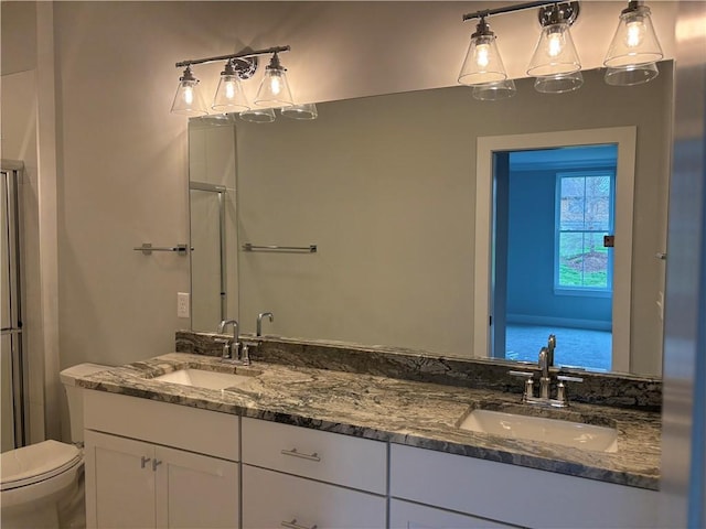 bathroom with toilet, double vanity, and a sink