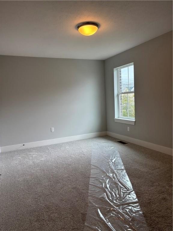 carpeted empty room with visible vents and baseboards