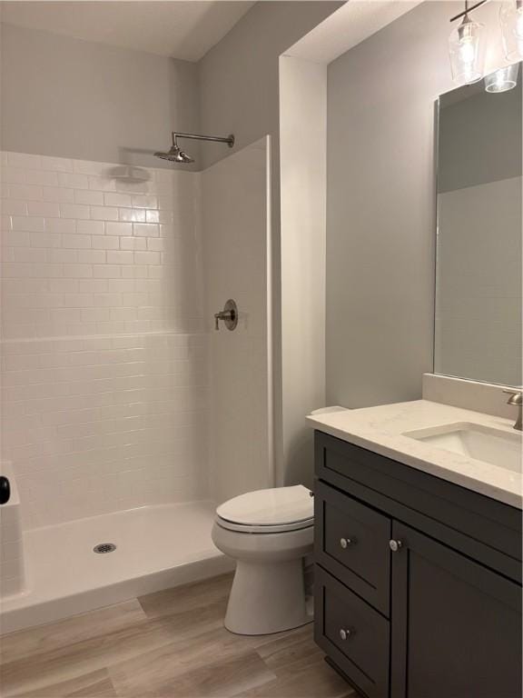 full bath with vanity, a stall shower, toilet, and wood finished floors