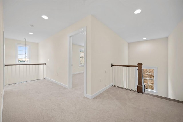 hallway featuring an upstairs landing, a healthy amount of sunlight, and carpet floors