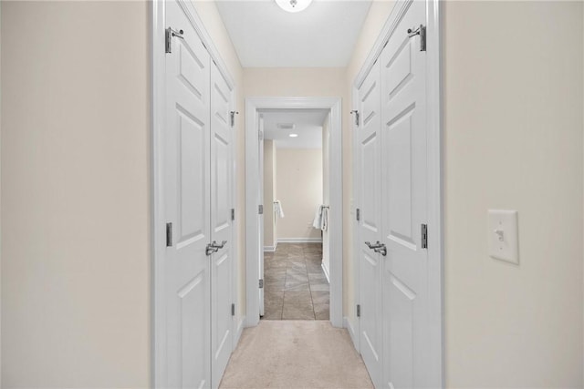 corridor featuring baseboards and light colored carpet