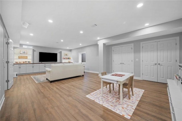 living room with recessed lighting, light wood finished floors, and baseboards