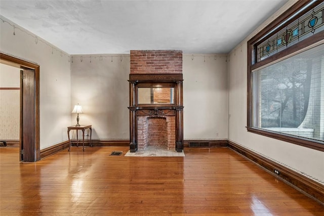 unfurnished living room with visible vents, hardwood / wood-style flooring, and baseboards