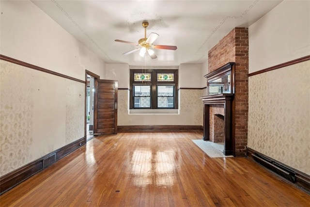 unfurnished living room featuring baseboards, a ceiling fan, hardwood / wood-style flooring, and a fireplace