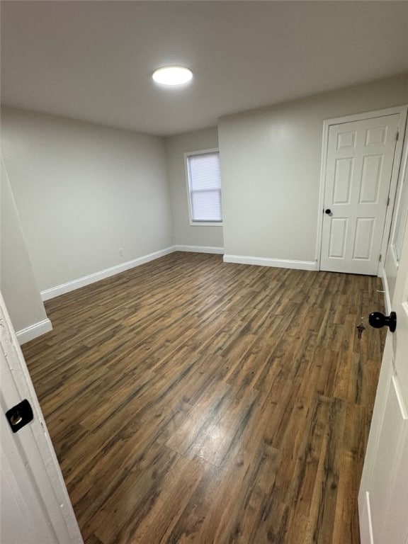 unfurnished room with dark wood finished floors and baseboards