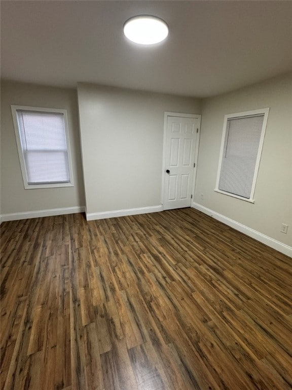 spare room featuring baseboards and dark wood finished floors