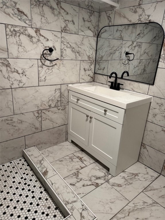 bathroom featuring tile walls, tiled shower, marble finish floor, and vanity