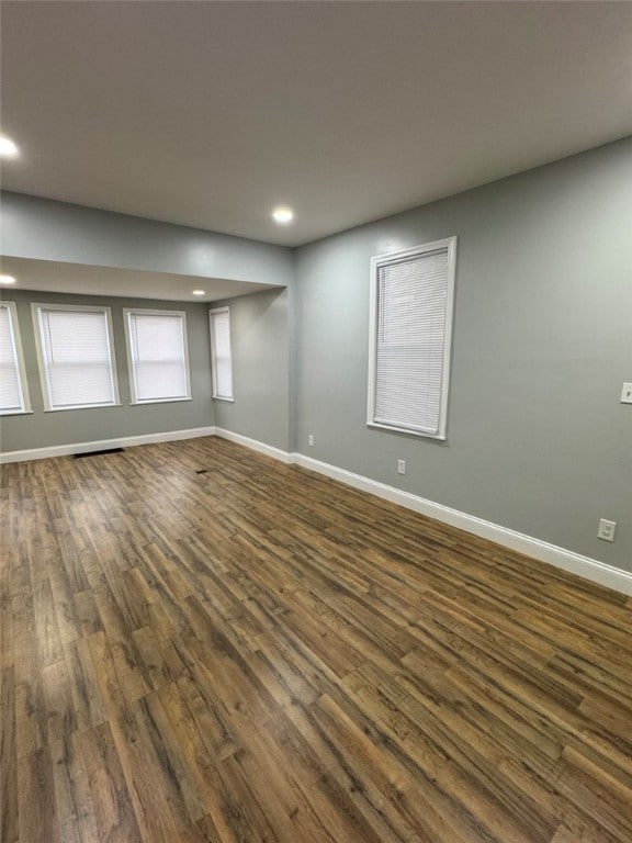 spare room featuring recessed lighting, baseboards, and dark wood finished floors