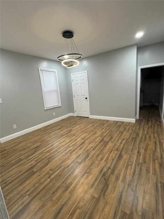interior space featuring dark wood-type flooring, a notable chandelier, and baseboards