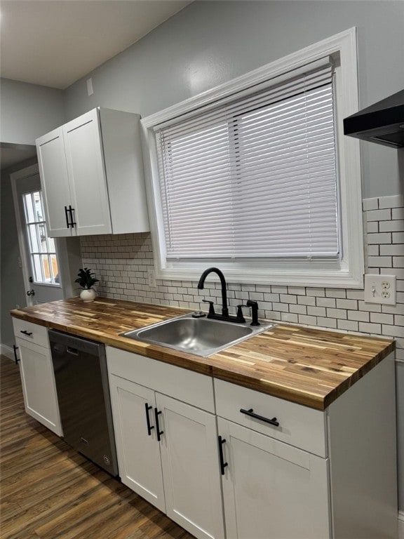kitchen with dark wood finished floors, tasteful backsplash, butcher block countertops, black dishwasher, and a sink