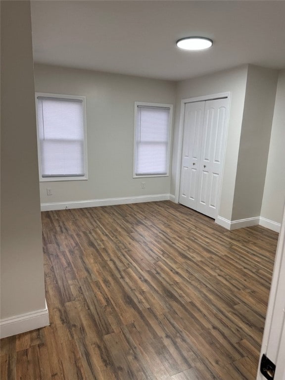 unfurnished bedroom featuring baseboards and dark wood-style flooring