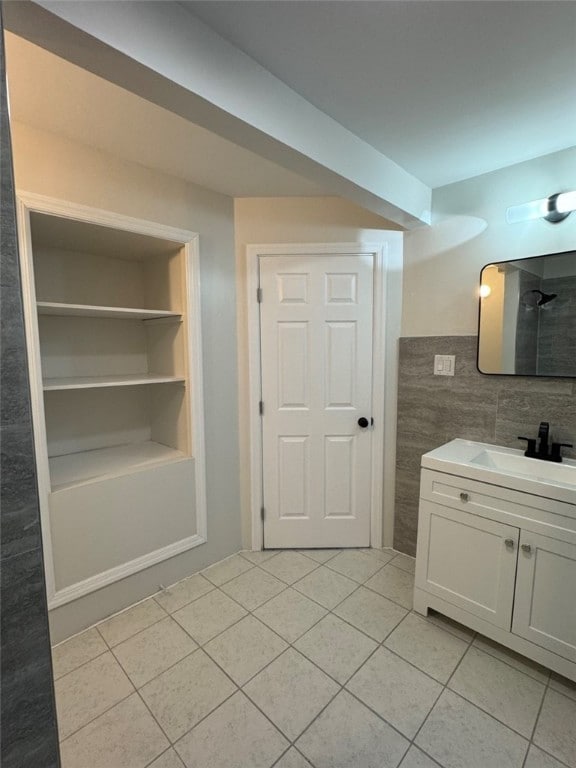 bathroom with tile walls, vanity, built in shelves, tile patterned floors, and walk in shower