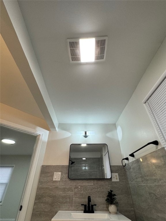 bathroom with a tile shower, visible vents, and a sink