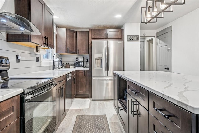 kitchen featuring light wood-style flooring, dark brown cabinets, a sink, stainless steel appliances, and extractor fan