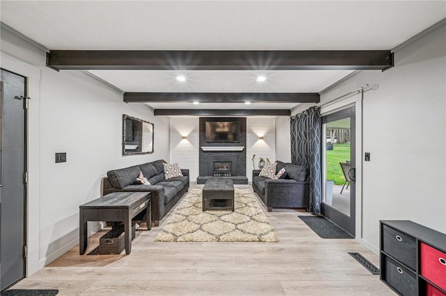 living area featuring visible vents, baseboards, a fireplace, beamed ceiling, and light wood finished floors
