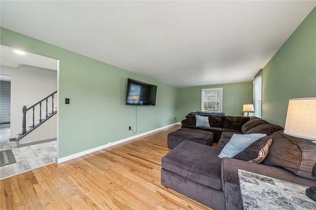 living room featuring stairs, baseboards, and wood finished floors