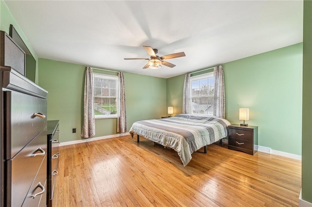bedroom with baseboards, ceiling fan, and light wood-style floors