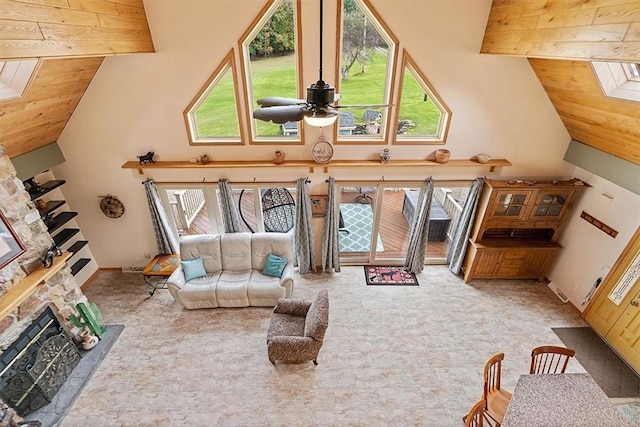 carpeted living area featuring wood ceiling, ceiling fan, beam ceiling, and a stone fireplace