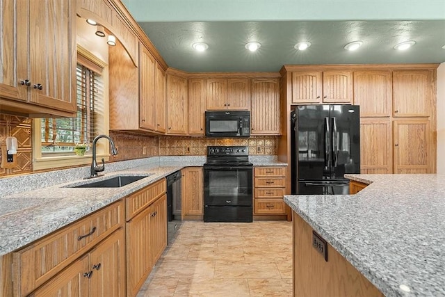 kitchen with a sink, backsplash, black appliances, and light stone counters