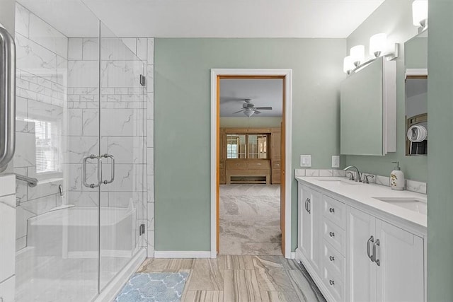 full bath with a sink, baseboards, marble finish floor, and a stall shower