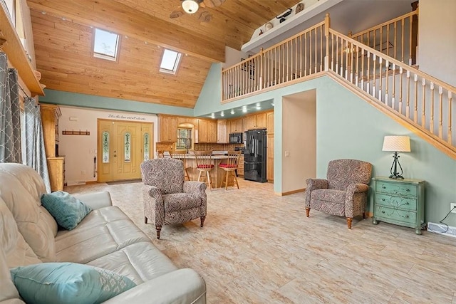 living area with high vaulted ceiling, baseboards, and a skylight