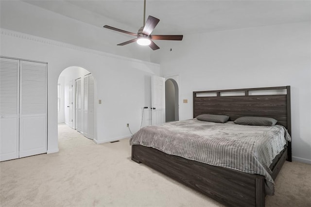 bedroom with arched walkways, baseboards, multiple closets, and carpet floors