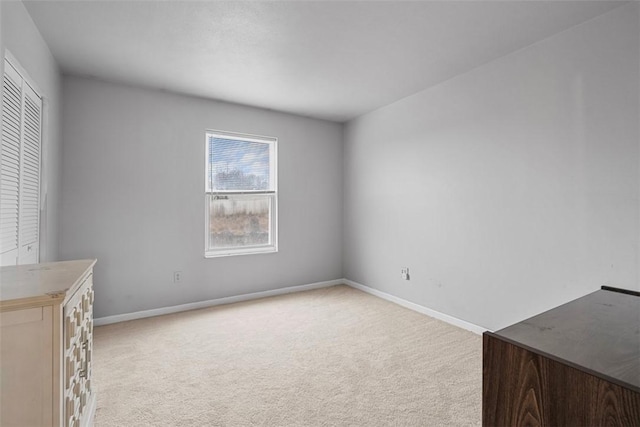 unfurnished bedroom with light colored carpet and baseboards