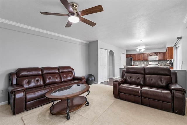 living room with baseboards, arched walkways, light carpet, and ceiling fan with notable chandelier