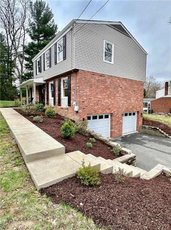 view of home's exterior with brick siding, driveway, and a garage