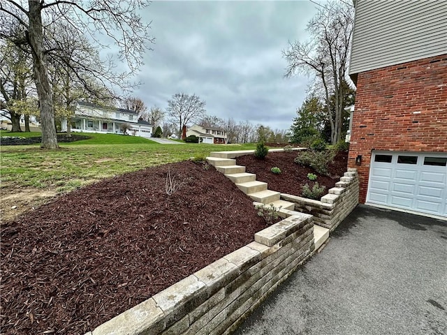 view of yard with an attached garage and aphalt driveway