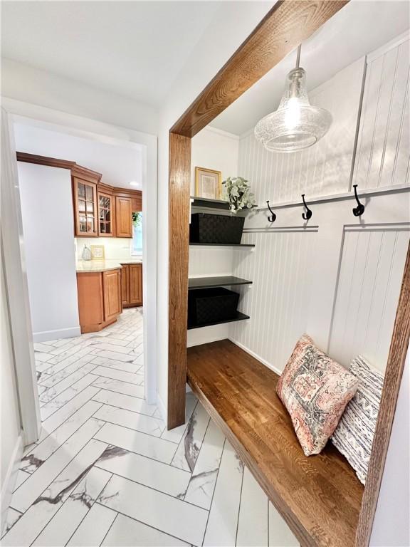 mudroom featuring baseboards, marble finish floor, and wainscoting