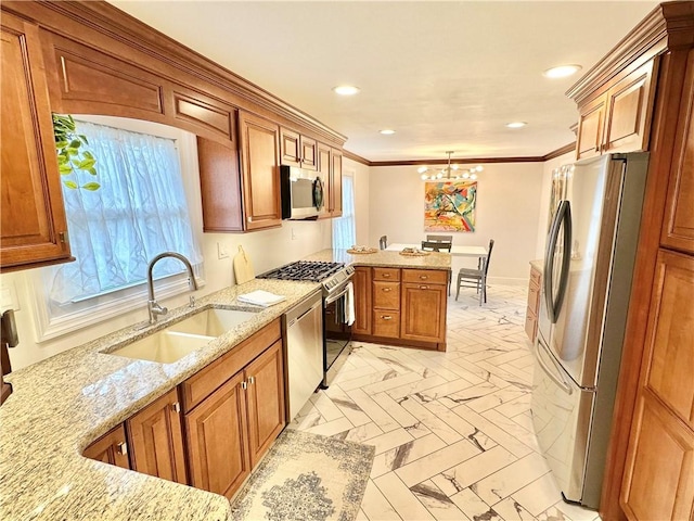 kitchen with brown cabinetry, a peninsula, appliances with stainless steel finishes, a sink, and a notable chandelier