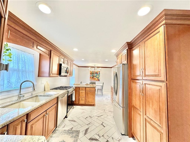kitchen featuring recessed lighting, a peninsula, light stone countertops, appliances with stainless steel finishes, and a sink