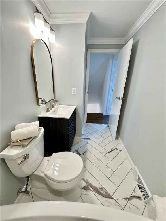 half bathroom with baseboards, ornamental molding, toilet, vanity, and marble finish floor