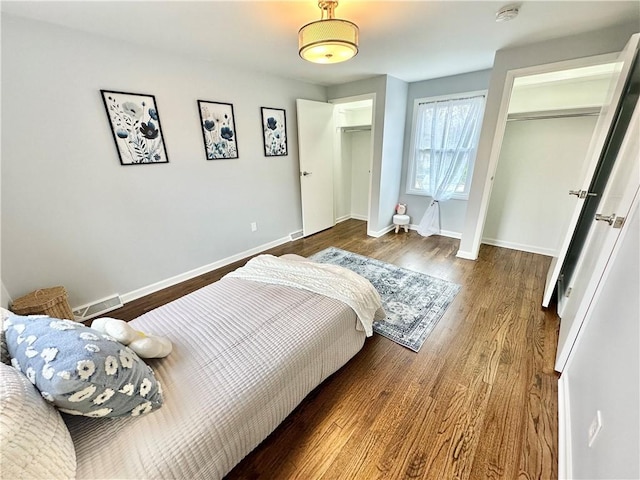 bedroom featuring wood finished floors, baseboards, and visible vents