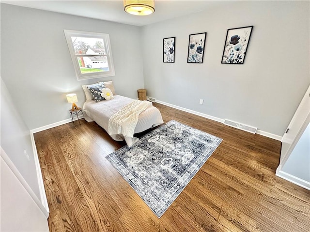 bedroom featuring visible vents, baseboards, and wood finished floors