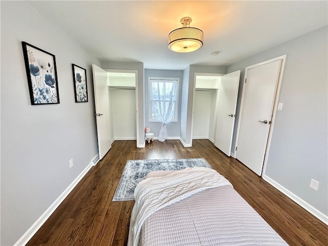 bedroom featuring baseboards, two closets, and wood finished floors