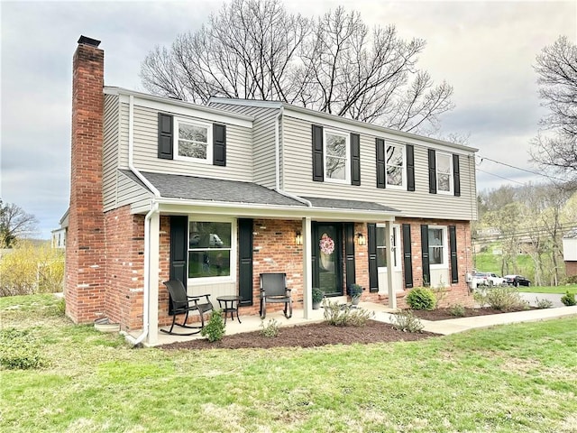 view of front of home with brick siding, a front lawn, and a chimney