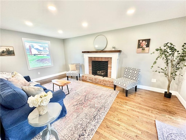living room with recessed lighting, a brick fireplace, baseboards, and wood finished floors