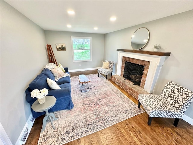living room with wood finished floors, a fireplace, baseboards, and recessed lighting