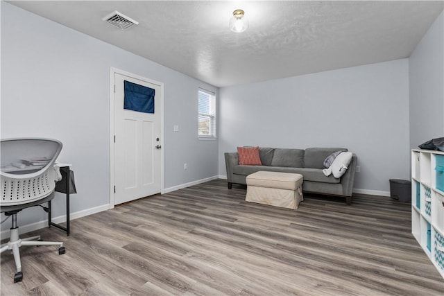 living room featuring wood finished floors, baseboards, and visible vents
