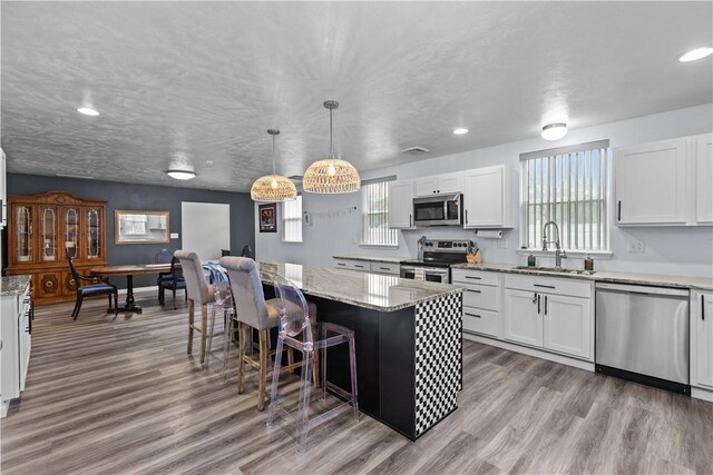 kitchen featuring wood finished floors, white cabinets, a sink, and appliances with stainless steel finishes