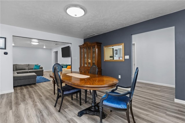 dining room with baseboards, wood finished floors, and a textured ceiling