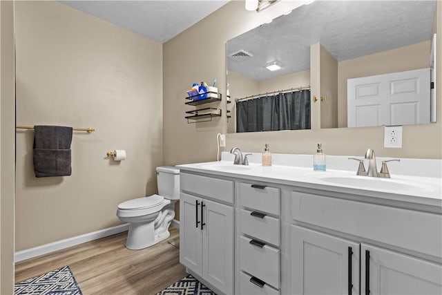 full bath featuring visible vents, toilet, wood finished floors, a sink, and baseboards