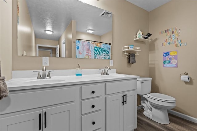 bathroom with baseboards, toilet, visible vents, a sink, and wood finished floors